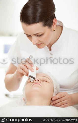 Professional beautician providing ultrasonic facial cleaning at beauty treatment salon