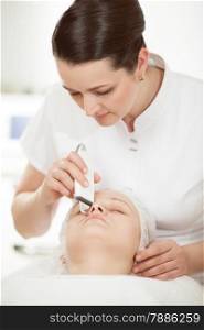 Professional beautician providing ultrasonic facial cleaning at beauty treatment salon