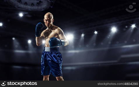 Professional box champion. Professional boxer fighting on arena in spotlights mixed media