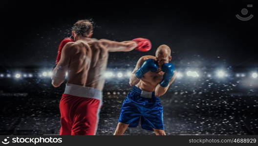 Professional box match. Two professional boxers fighting on arena in spotlights mixed media