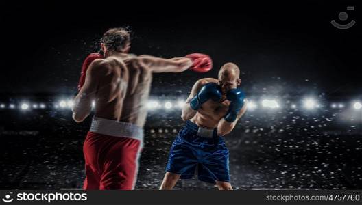 Professional box match. Two professional boxers fighting on arena in spotlights mixed media