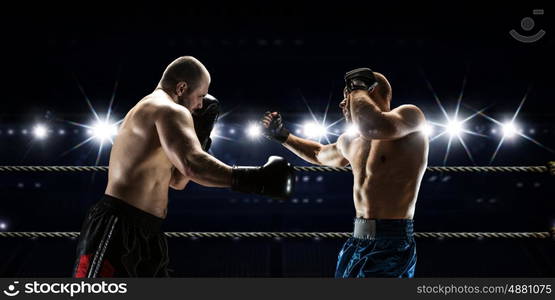 Professional box match. Two professional boxers fighting on arena in spotlights mixed media