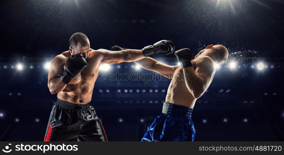 Professional box match. Two professional boxers fighting on arena in spotlights mixed media