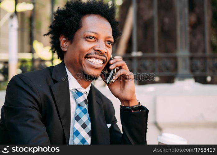 Professional businessman talking on the phone while sitting on stairs outdoors. Business concept.