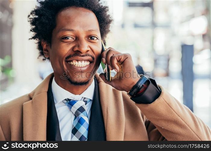 Professional businessman talking on the phone while walking outdoors on the street. Business concept.