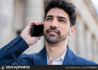Professional businessman talking on the phone while walking outdoors on the street. Business concept.