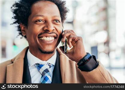 Professional businessman talking on the phone while walking outdoors on the street. Business concept.. Businessman talking on phone outdoors.