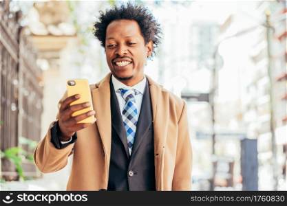 Professional businessman using his mobile phone while standing outdoors on the street. Business concept.