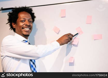 Professional businessman using sticky notes on whiteboard to share ideas for business strategy plan. Business concept.