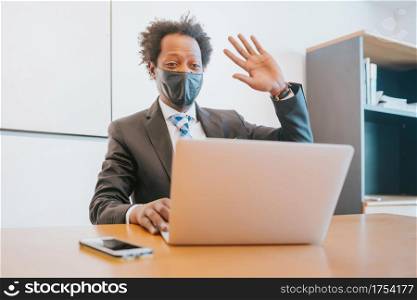 Professional businessman wearing face mask and having a video call with laptop at office. New normal lifestyle. Business concept.