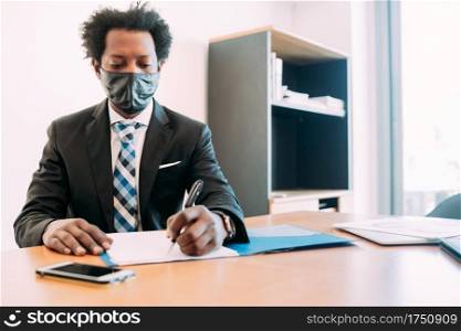 Professional businessman wearing face mask  while working with some files and documents at his office. New normal lifestyle concept. Business concept.