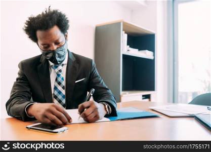 Professional businessman wearing face mask while working with some files and documents at his office. New normal lifestyle concept. Business concept.