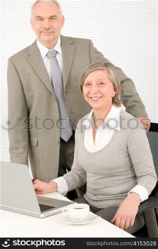 Professional businesspeople behind office table with laptop