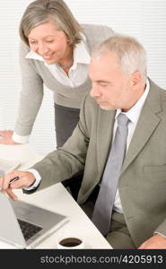 Professional businesspeople behind office table with laptop