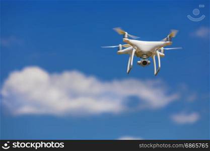 Professional camera drone flying in clear blue sky partly clouded