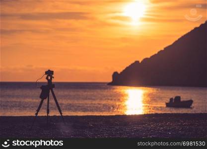 Professional camera taking picture film video of scenic orange sunrise or sunset over sea surface, Greece Peloponnese.. Camera taking picture of sunrise over sea surface