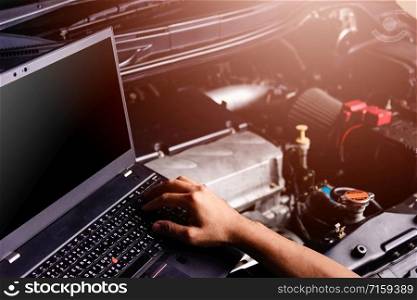 Professional car repair or maintenance mechanic engine working service with laptop computer at workshop