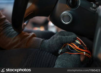 Professional car thief hacking ignition lock, criminal lifestyle. Hooded male robber breaks vehicle security system on parking. Auto robbery, automobile crime