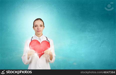 Professional care for your heart. Attractive healthcare woman worker with red heart symbol