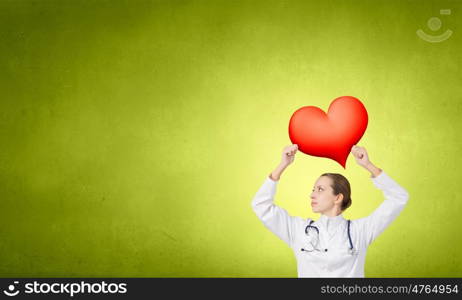 Professional care for your heart. Attractive healthcare woman worker with red heart symbol