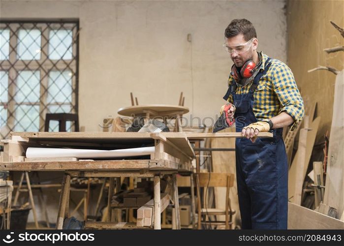 professional carpenter cutting wooden plank with handsaw workshop