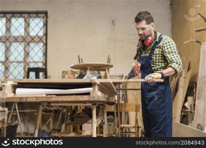 professional carpenter cutting wooden plank with handsaw workshop