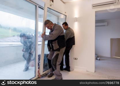 professional carpenters installing a balcony door in a new apartment with panoramic windows