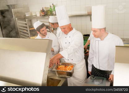 Professional chef cook with team prepare food in industrial kitchen