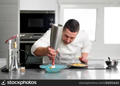 Professional chef holding a foam siphon in a restaurant kitchen. High quality photo. Professional chef holding a foam siphon in a restaurant kitchen.