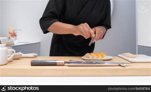 Professional chef preparing and cooking raw fresh fish ingredient on the table with knife for delicious sushi and sashimi meal, Person making luxury omakase fine dining Japanese food restaurant dinner
