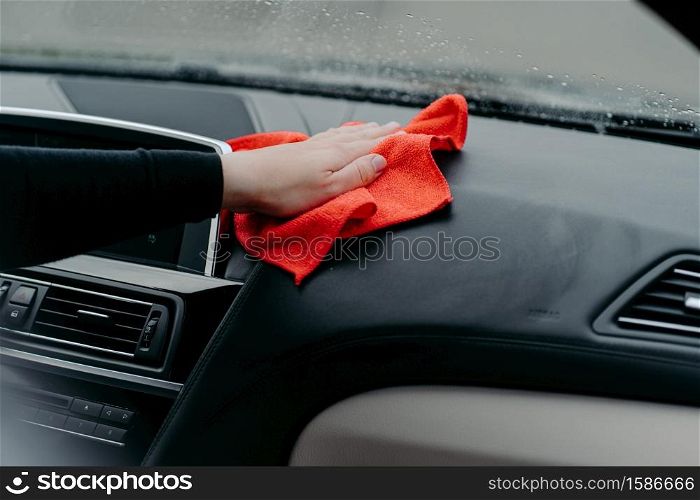 Professional cleaner and car cleaning concept. Unrecognizable man cleans car interior with cloth. Selective focus. Washing auto dashboard with rag