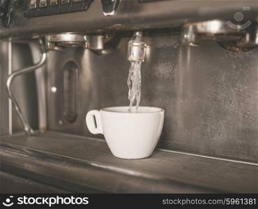 Professional coffee machine with a small white cup getting water dispensed into it