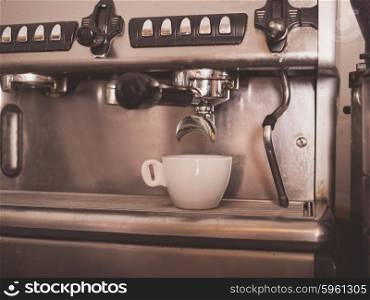 Professional coffee machine with a small white cup ready for coffee being dispensed