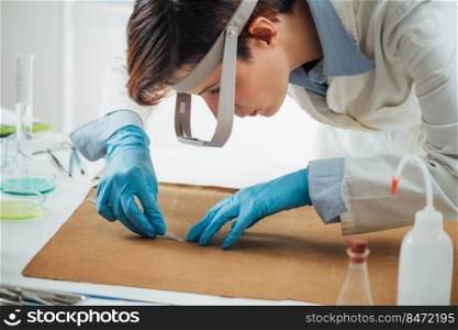 Professional conservator removing the dirt from reverse side of the antique oil painting canvas. Conservator Removing the Dirt from Reverse Side of the Antique Oil Painting Canvas