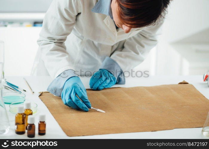 Professional conservator removing the dirt from reverse side of the antique oil painting canvas. Conservator Removing the Dirt from Reverse Side of the Antique Oil Painting Canvas