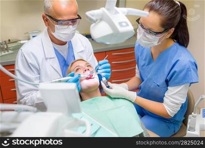 Professional dentist and nurse doing operation on female patient