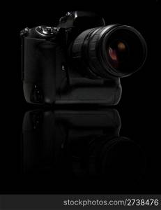 Professional digital camera over black background. With reflection.