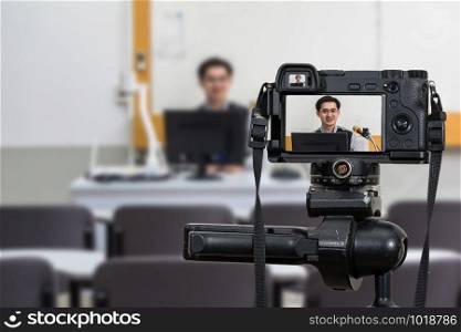 Professional digital Mirrorless camera on the tripod recording video blog of Asian teacher in the classroom,Camera for photographer or Video and Technology Live Streaming concept,University education