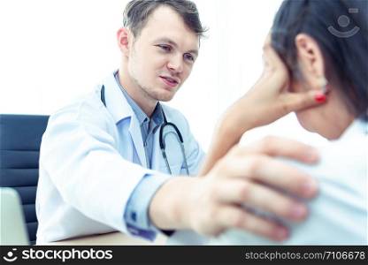 Professional doctor man with stethoscope reassuring woman patient on workplace in hospital.Professional medical doctor comforting patient at consulting room.Medical ethics and trust healthcare concept