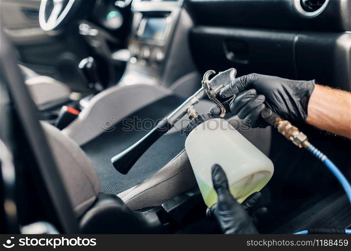 Professional dry cleaning of car interior. Carwash service, male worker using spray. Professional dry cleaning of car interior