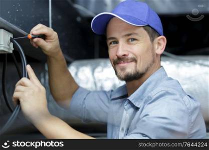 professional electrician man fixing unit of an air conditioner