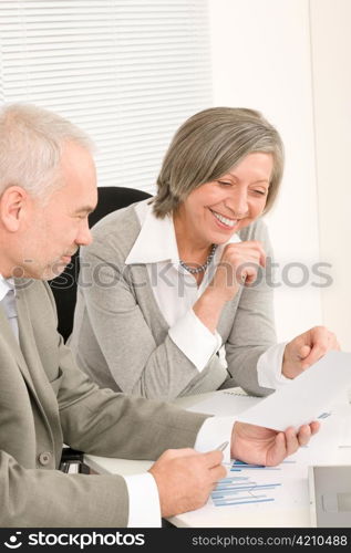 Professional elegant happy senior businesswoman looking graphs with man colleague