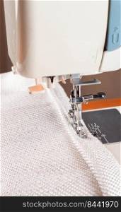 Professional equipment. Modern sewing machine with special pressure foot. The process of sewing a decorative edging cord of white item of clothing.. sewing machine. the process of sewing a decorative cord of white fabric.