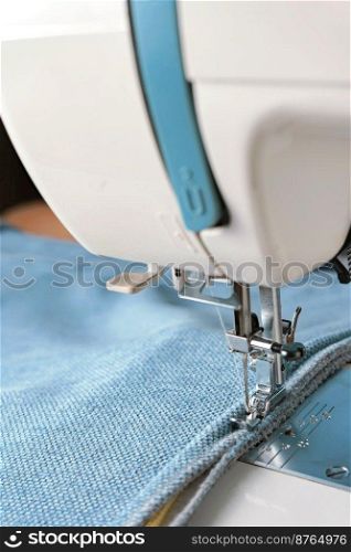 Professional equipment. Modern sewing machine with special pressure foot. The process of sewing a decorative edging cord of blue item of clothing.. Sewing machine. the process of sewing a decorative cord of blue fabric.