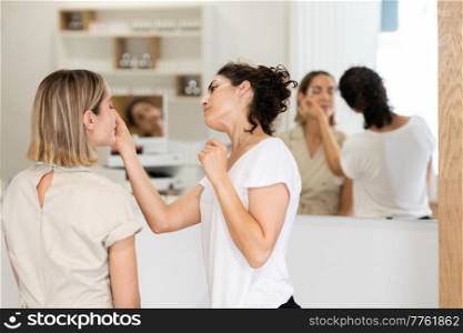 Professional female beautician doing skincare treatment on face of woman in modern beauty center. Cosmetologist doing beauty procedure on face of client