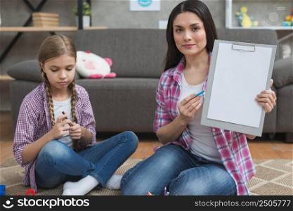 professional female psychologist sitting with girl carpet showing white paper clipboard