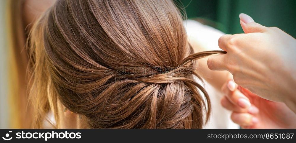 Professional hairdresser doing hairstyle for a beautiful brunette young woman with long hair. Concept of fashion and beauty. Professional hairdresser doing hairstyle for a beautiful brunette young woman with long hair. Concept of fashion and beauty.