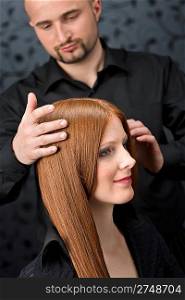 Professional hairdresser with long red hair fashion model at black luxury salon