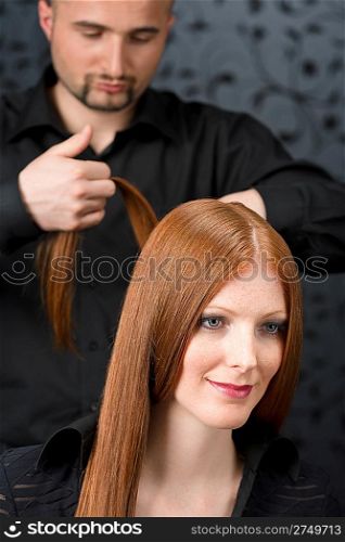 Professional hairdresser with long red hair fashion model at black luxury salon