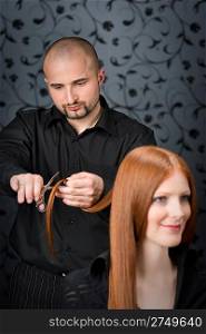 Professional hairdresser with long red hair fashion model at luxury salon, hair cut with scissors
